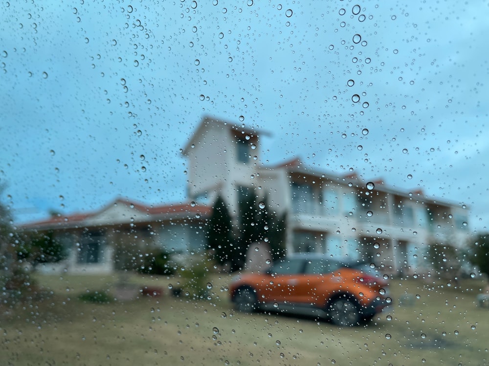 Une voiture est garée devant une maison un jour de pluie