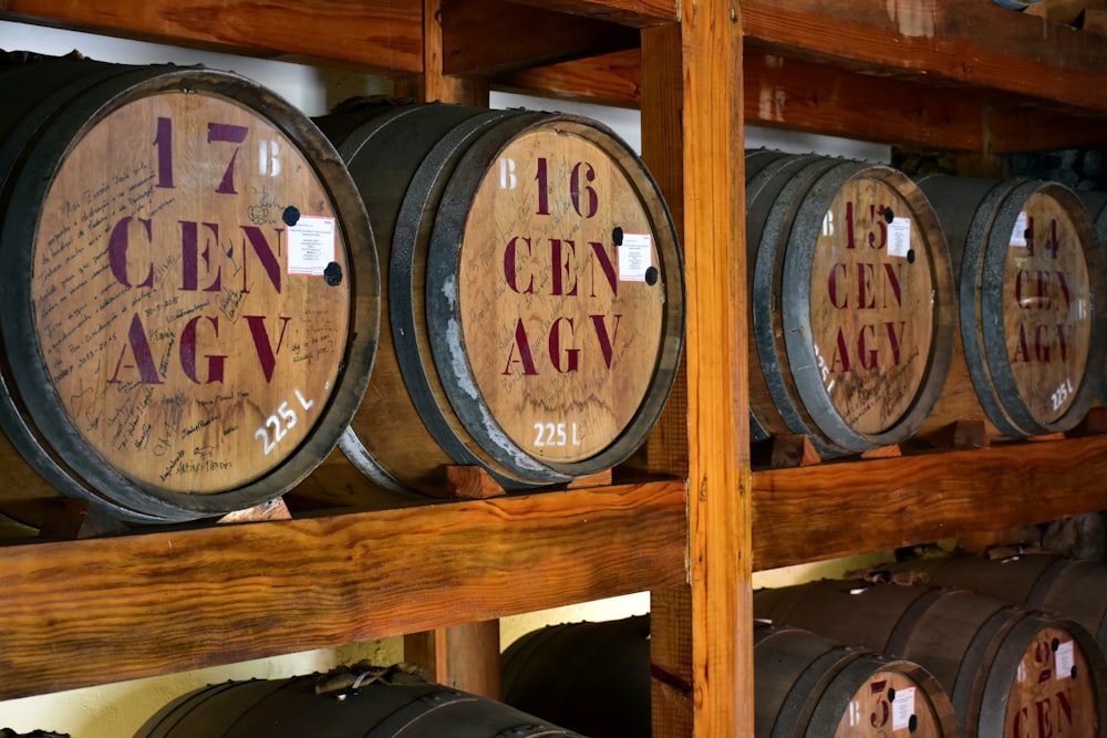 a row of wine barrels sitting on top of a wooden shelf