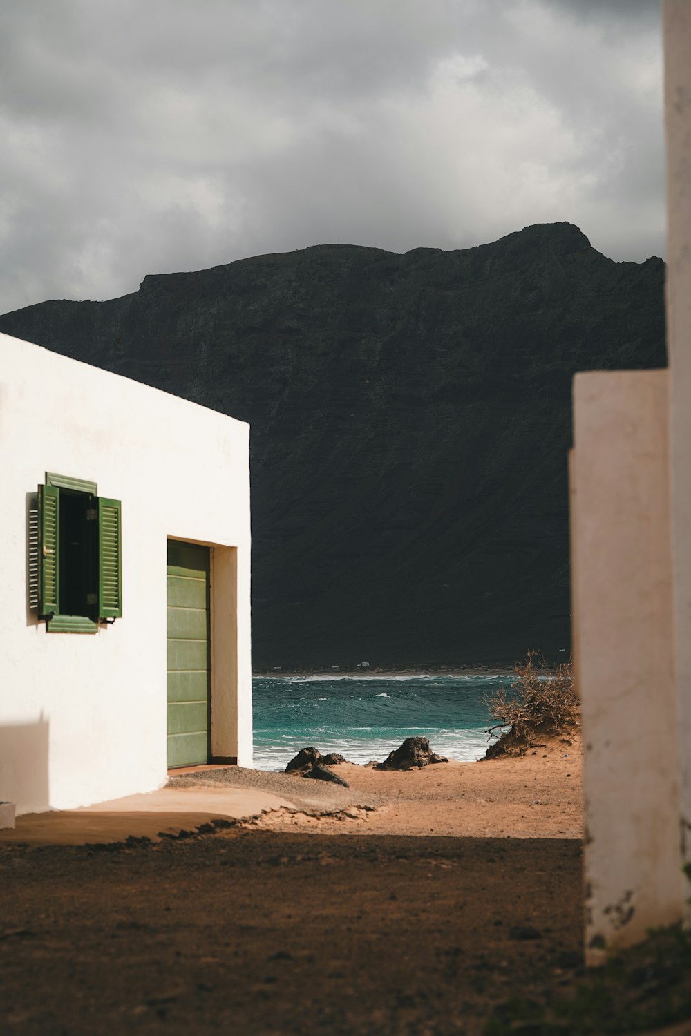 a white building with green shutters near the ocean