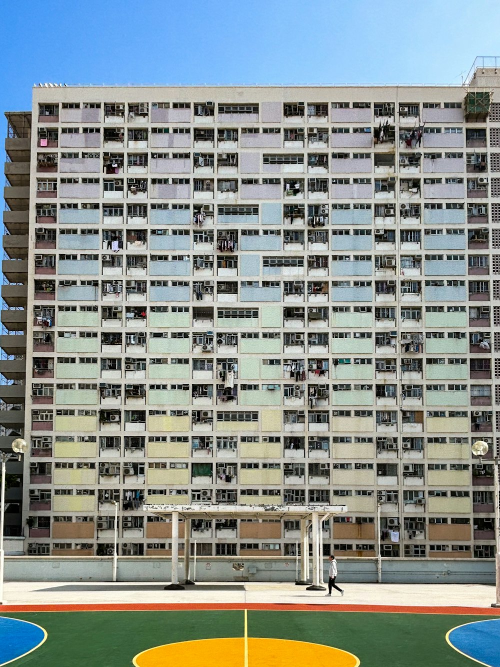 un grand bâtiment avec un terrain de basket en face