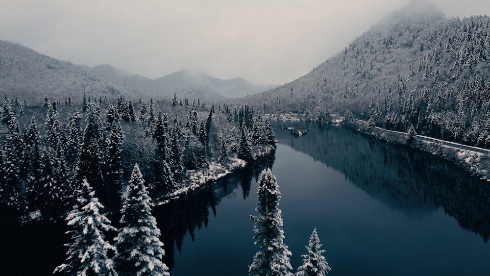 a lake surrounded by snow covered trees in the mountains
