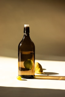 a bottle of liquid with a lemon on a table