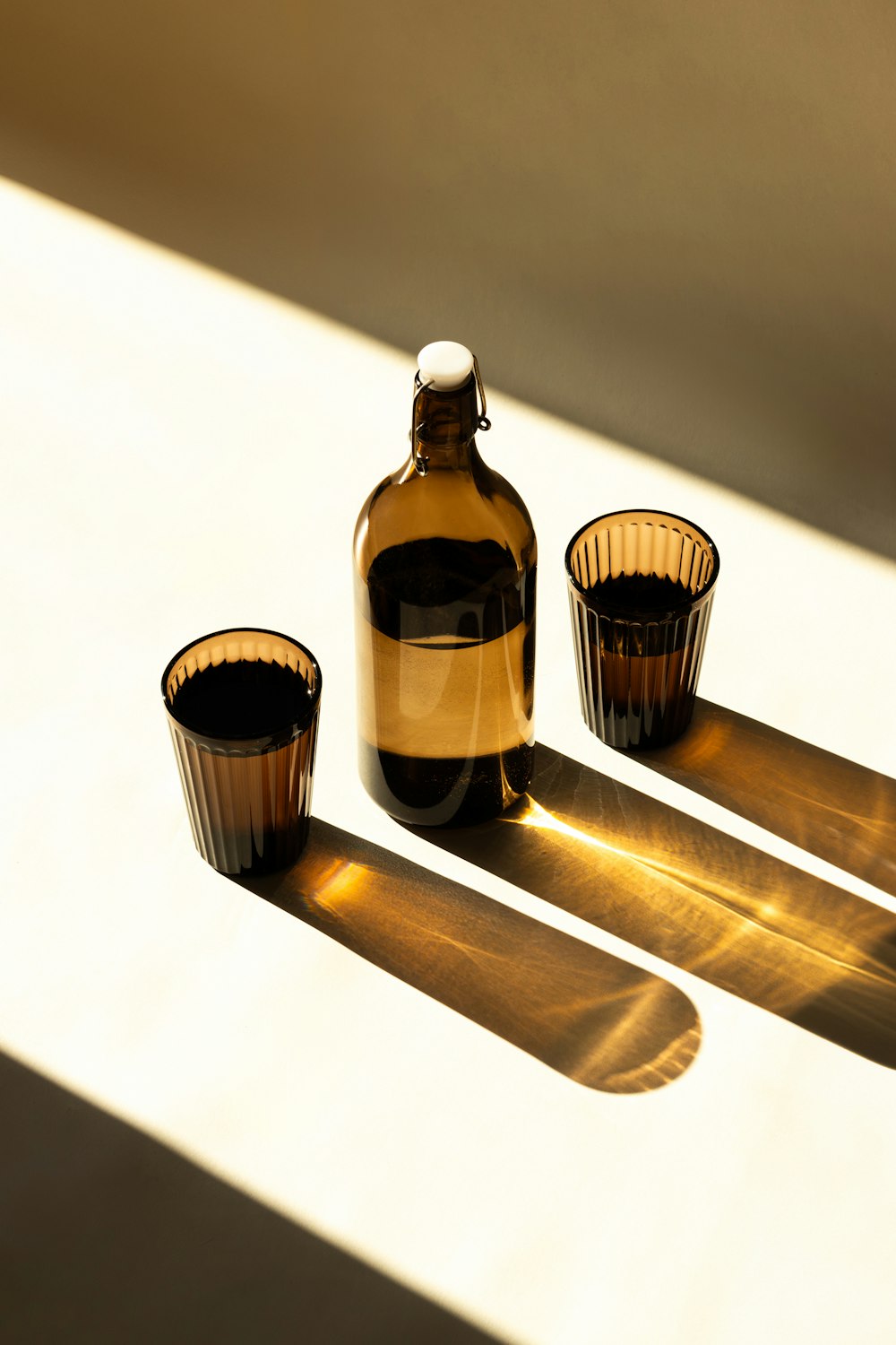 a bottle and three cups on a table