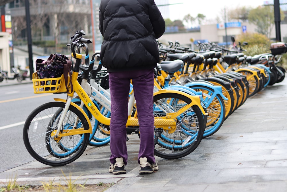 a person standing next to a row of parked bicycles