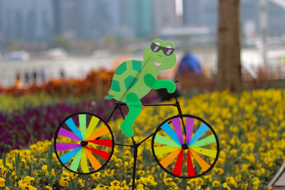 a paper cut out of a frog riding a bicycle