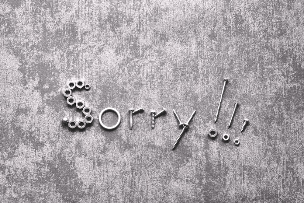 the word sorry written in metal letters on a concrete wall