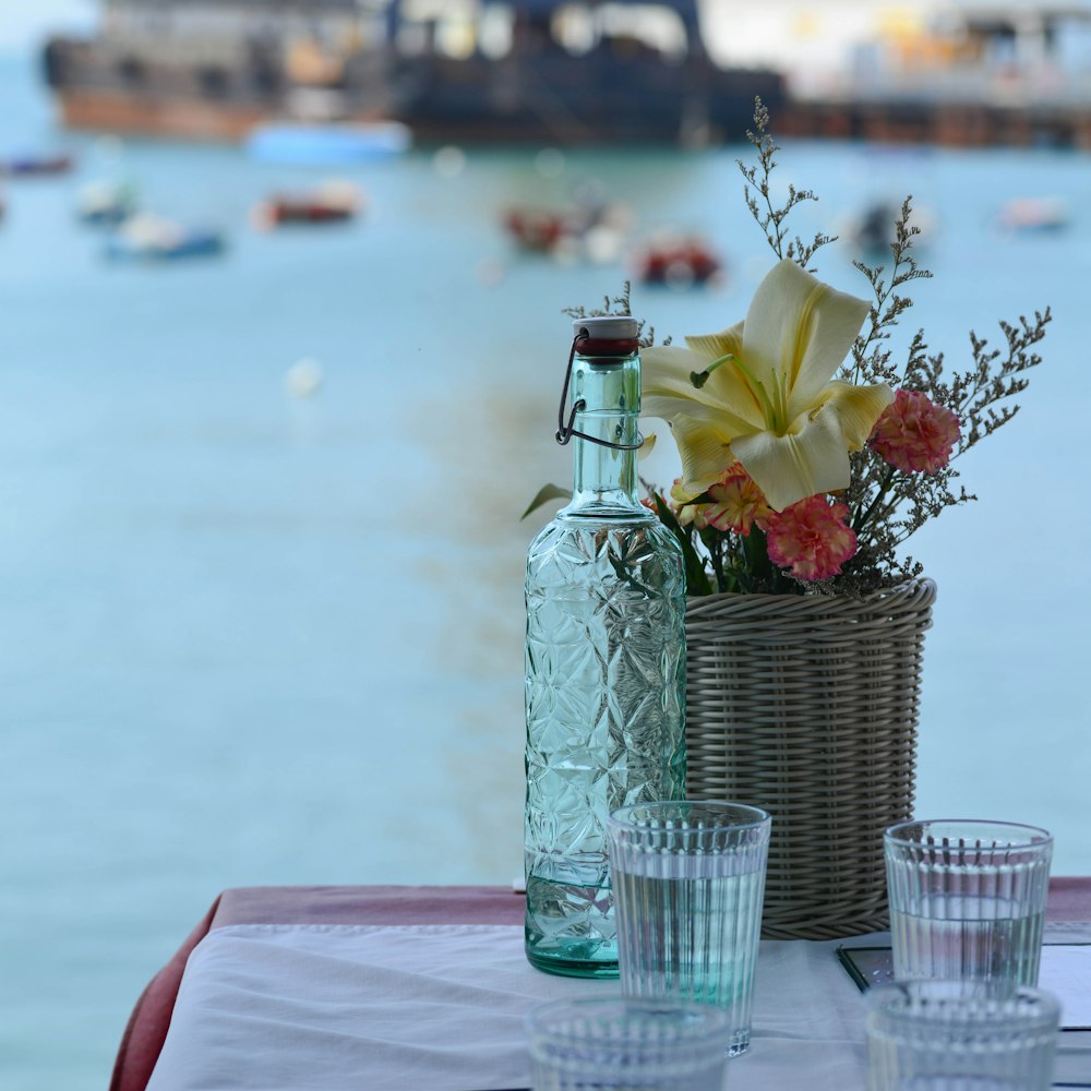 a table with a vase of flowers and two glasses on it