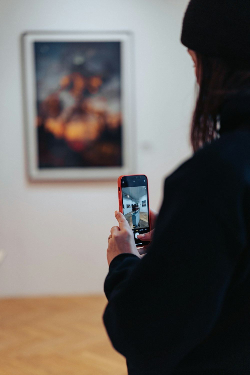 a woman taking a picture of a painting on a wall