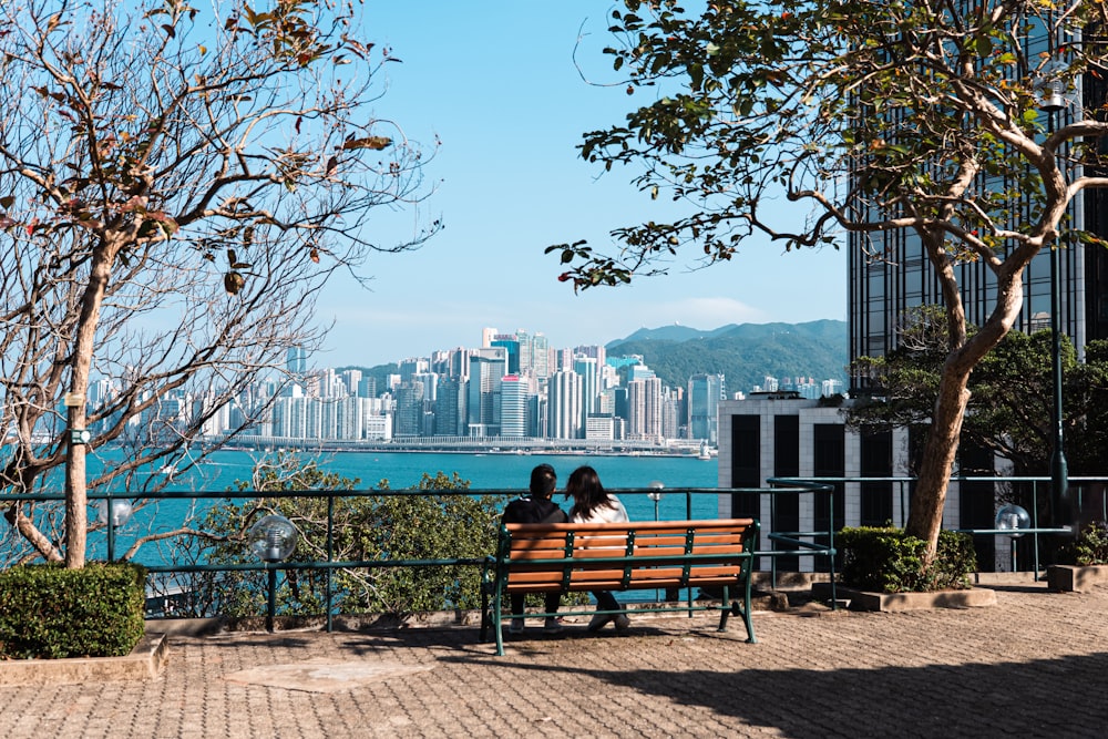 two people sitting on a bench overlooking the water