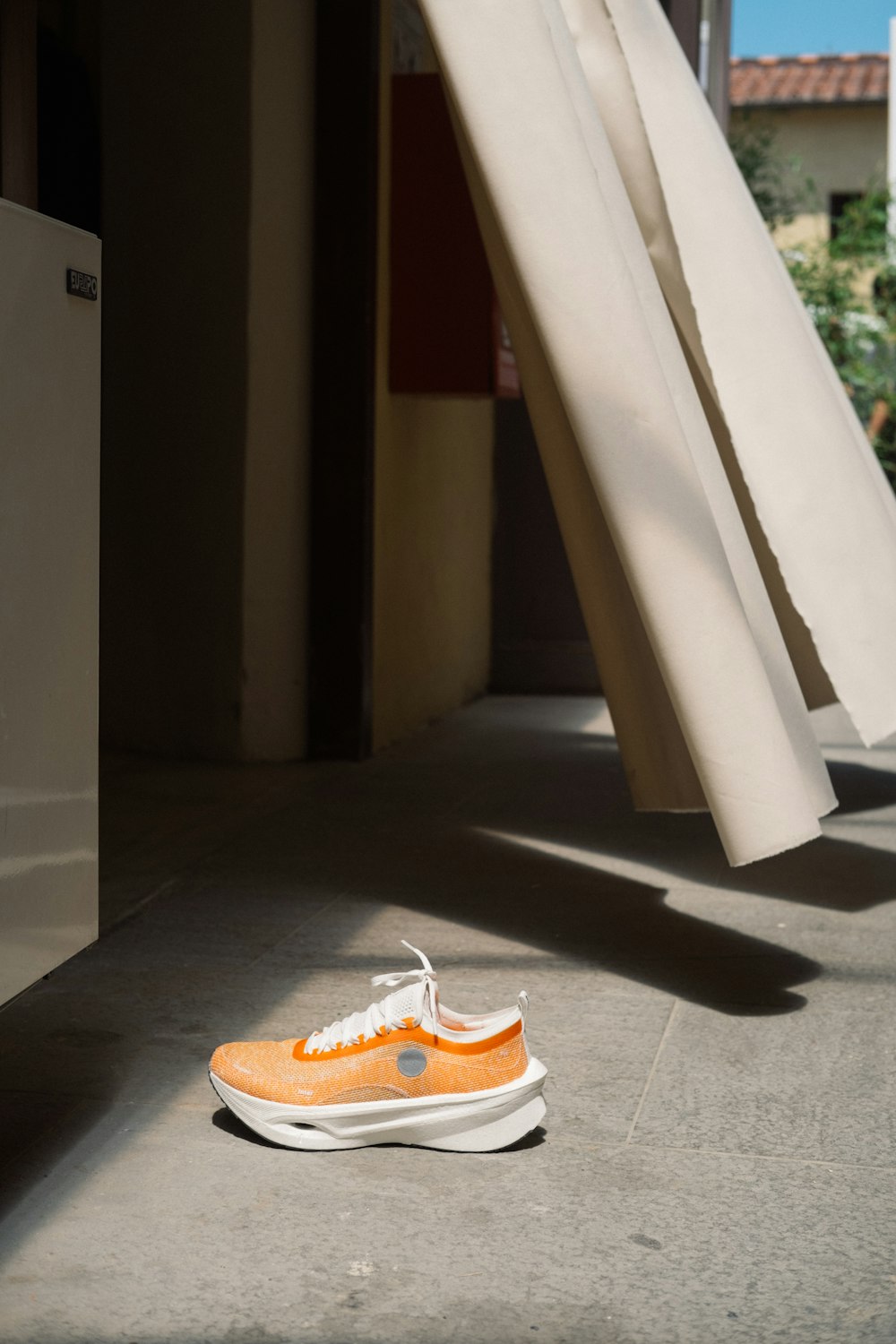 ein Paar orange-weiße Schuhe, die auf dem Boden sitzen