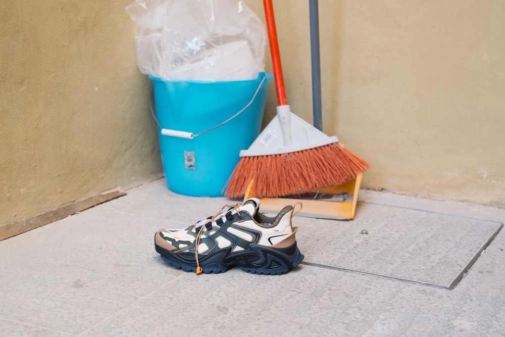 a pair of shoes sitting on the ground next to a broom