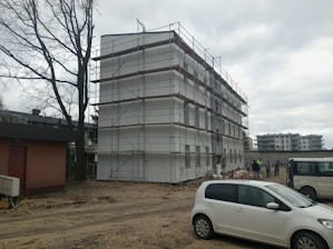 a white car parked in front of a building under construction