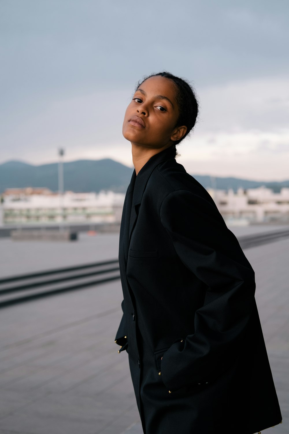 a woman in a black suit standing on a sidewalk