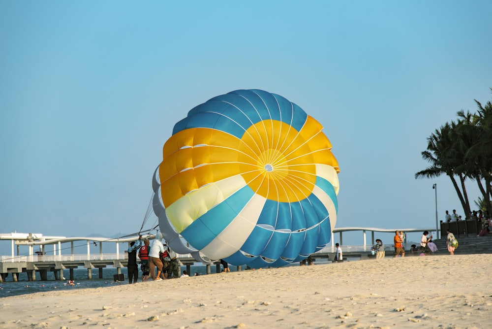 a large blue and yellow balloon sitting on top of a sandy beach
