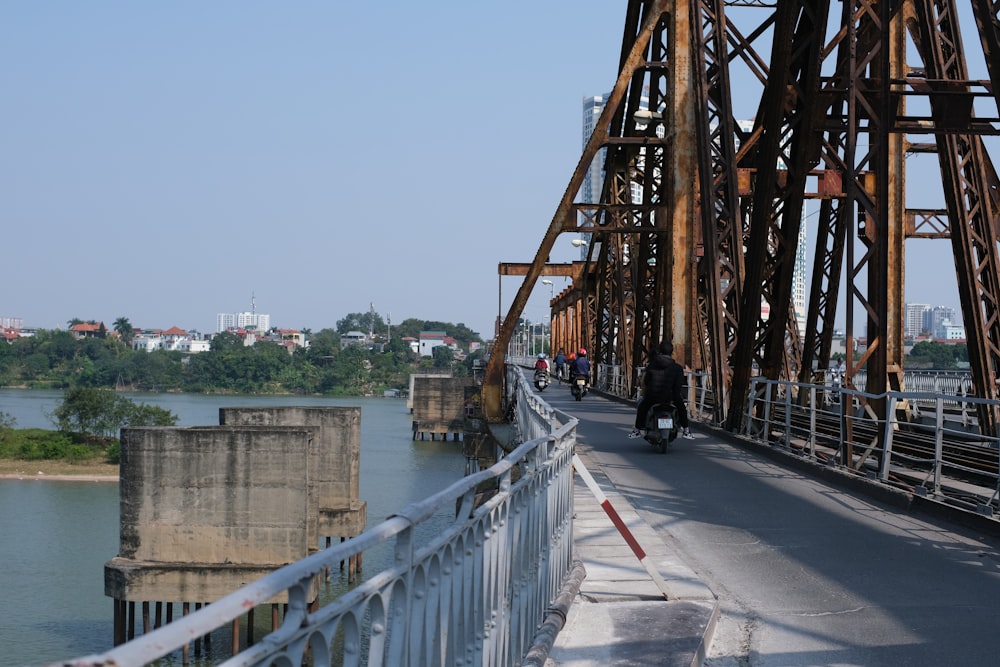 a motorcycle driving across a bridge over a river