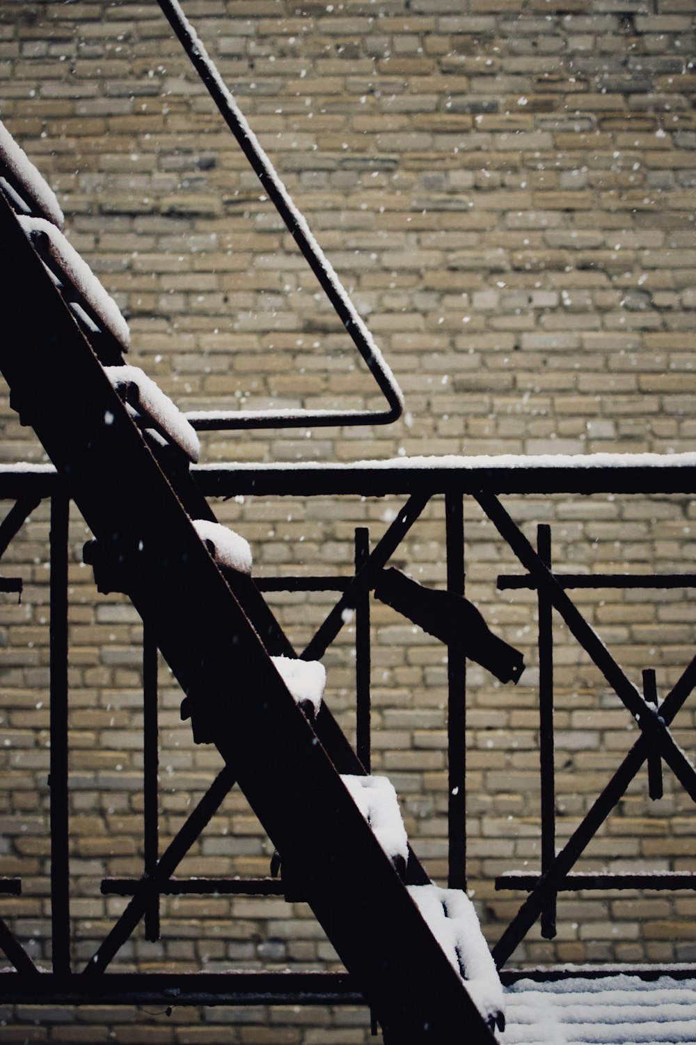 a snow covered stair case next to a brick wall