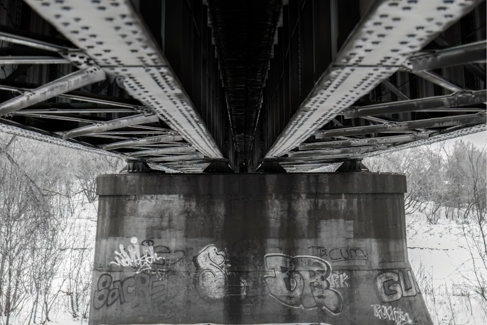 a black and white photo of a bridge with graffiti on it