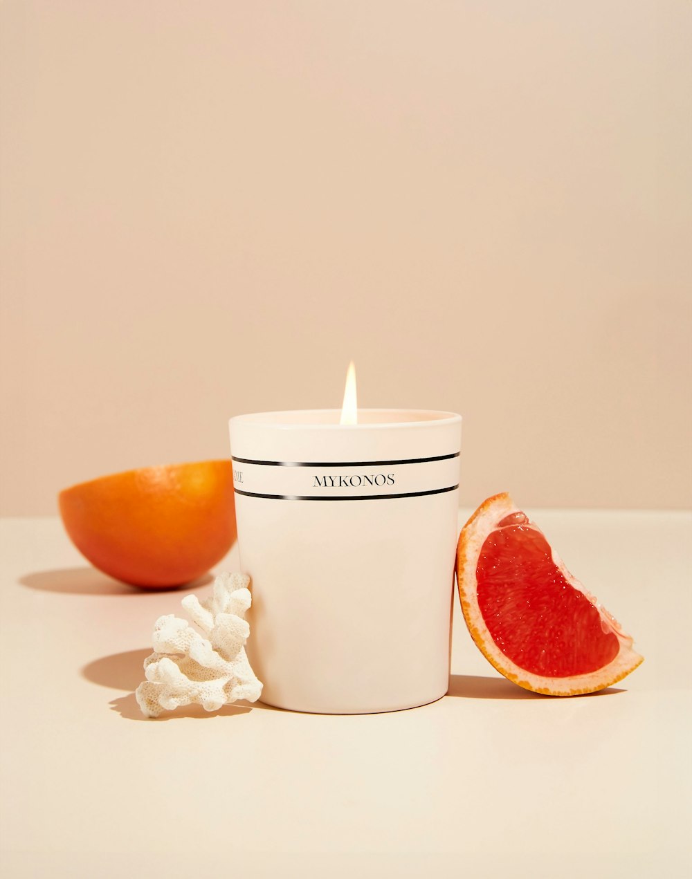 a candle that is sitting next to a grapefruit