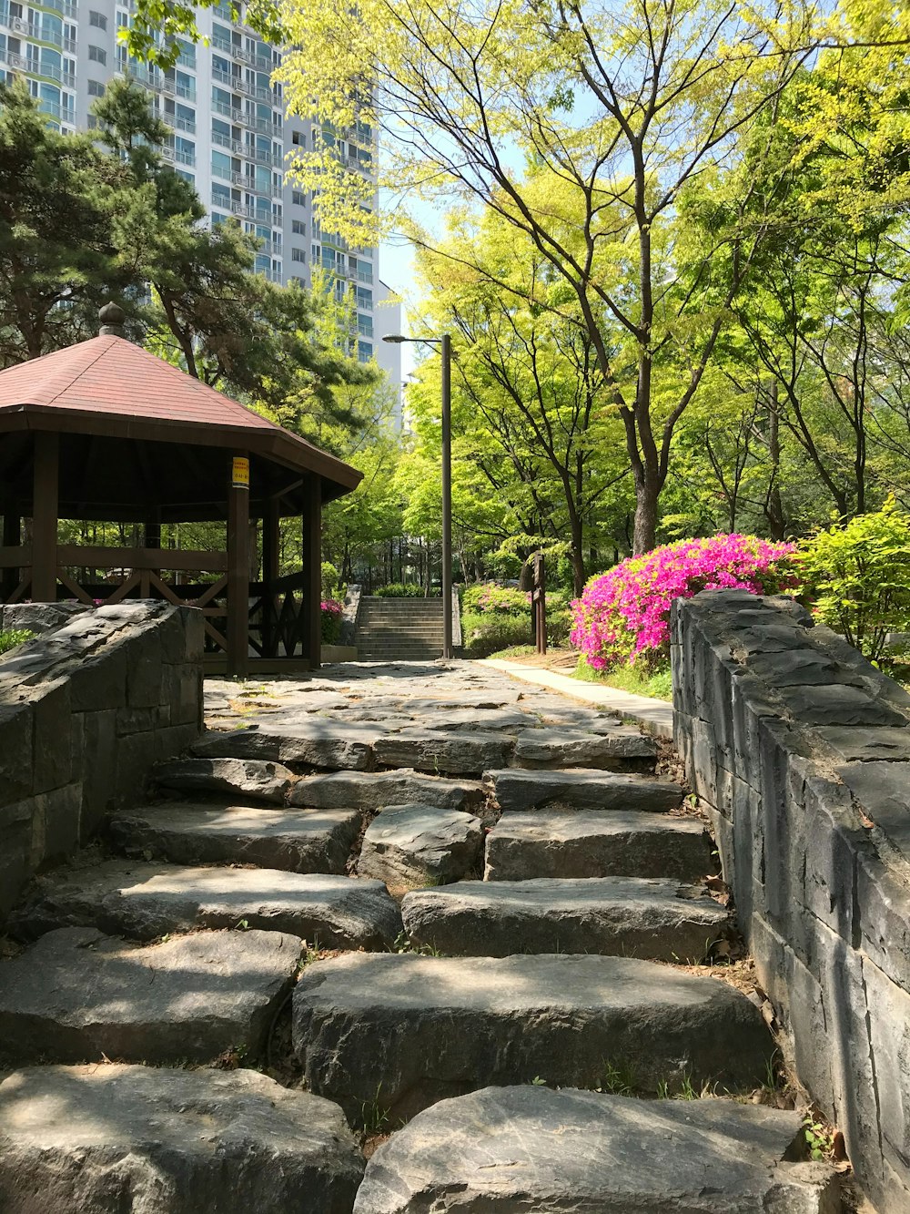 a stone path in a park with a gazebo in the background