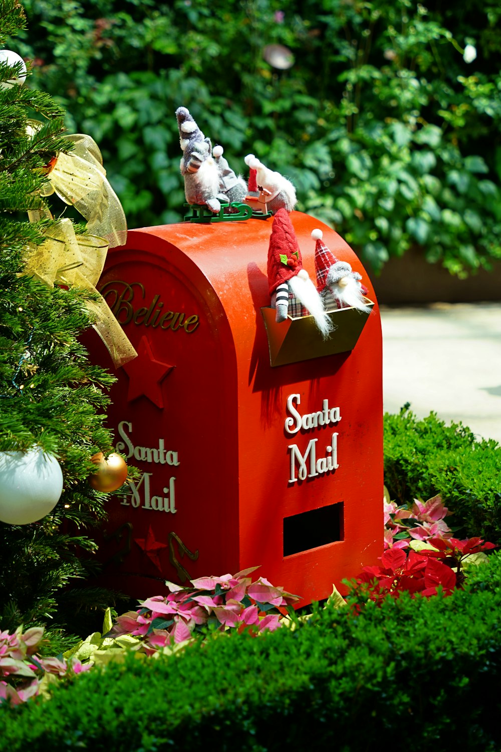 a red mailbox sitting next to a christmas tree