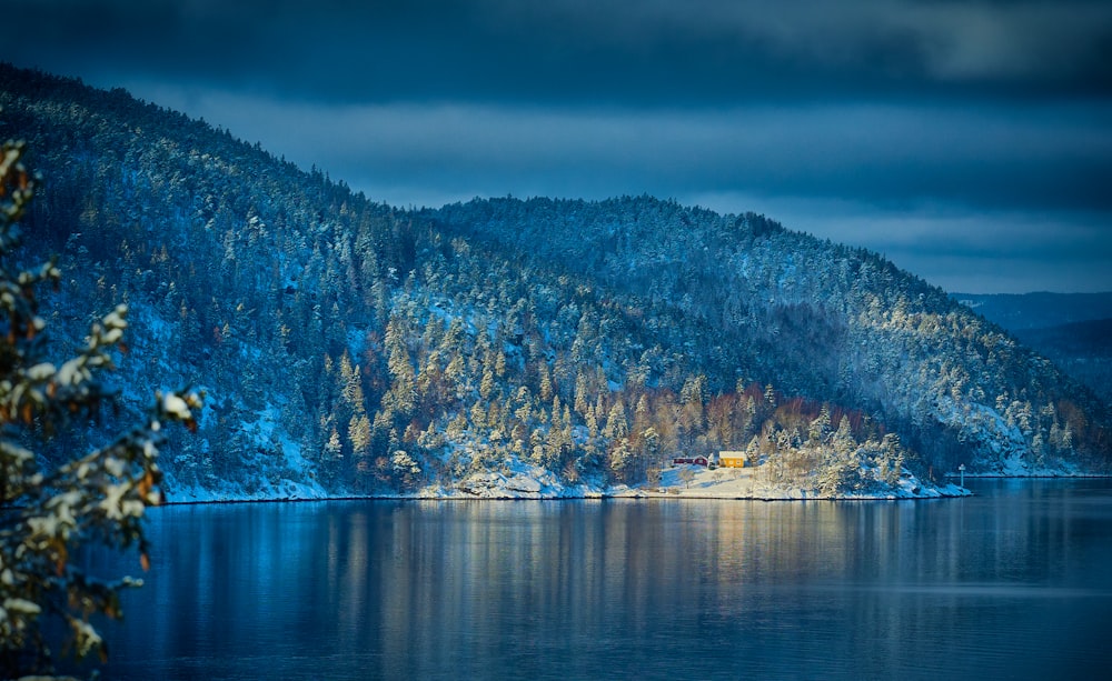 a lake surrounded by snow covered mountains under a cloudy sky