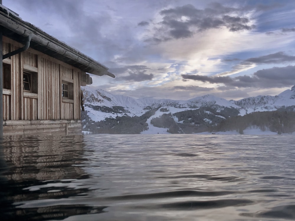 una casa in mezzo a un lago con le montagne sullo sfondo