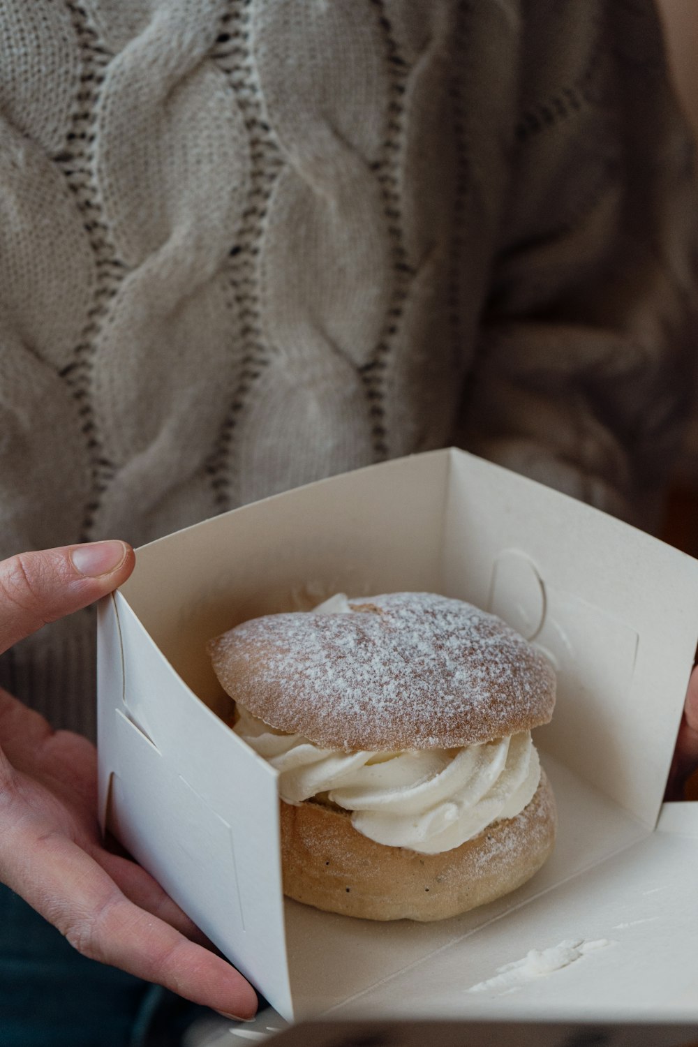 a person holding a box with a pastry inside of it