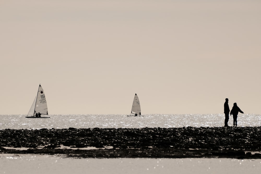 a couple of people standing on top of a beach near the ocean