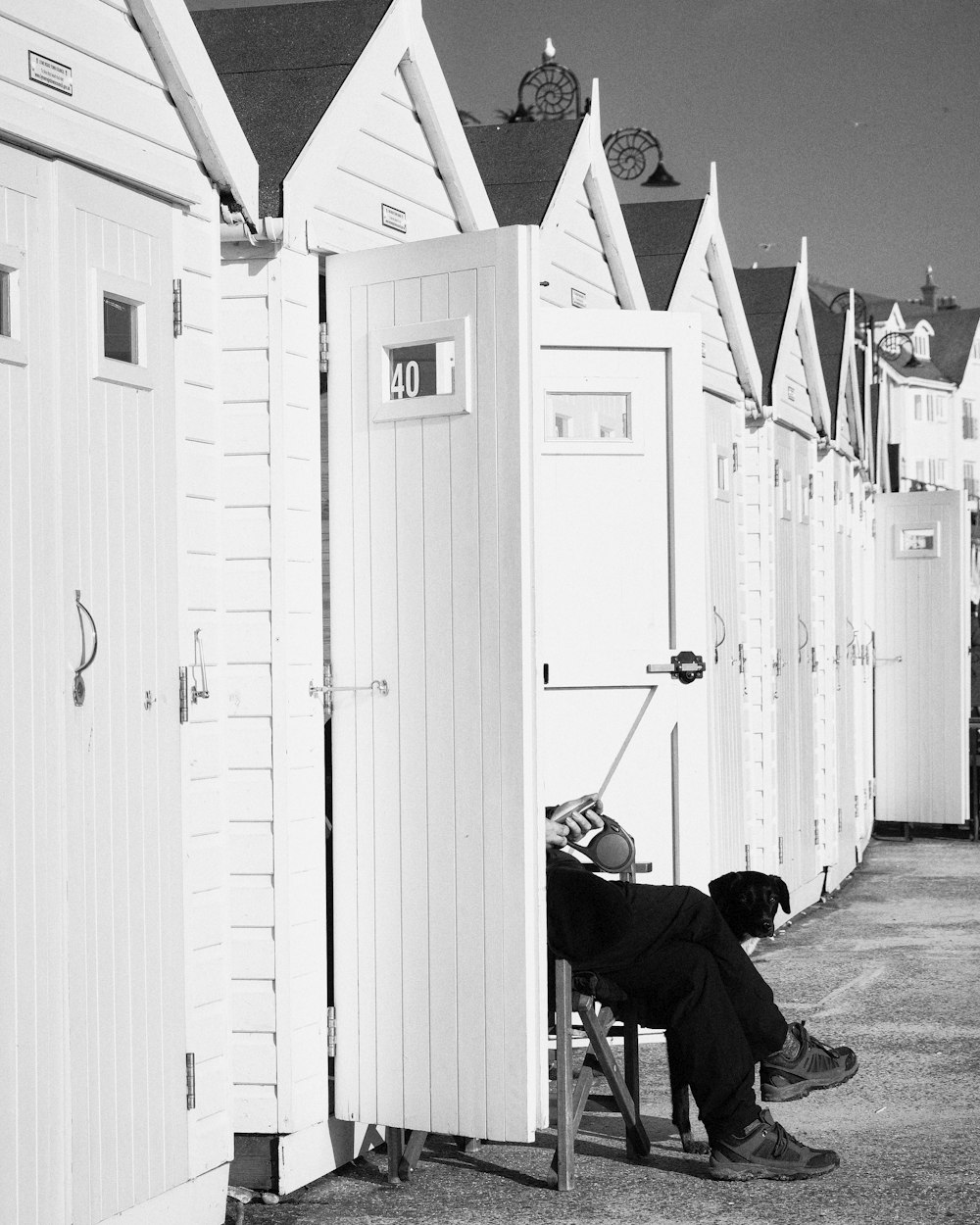 a person sitting on a chair in front of a row of beach huts