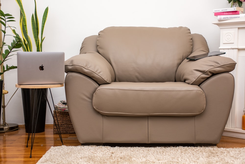 uma cadeira de couro marrom sentada em uma sala de estar ao lado de um computador portátil