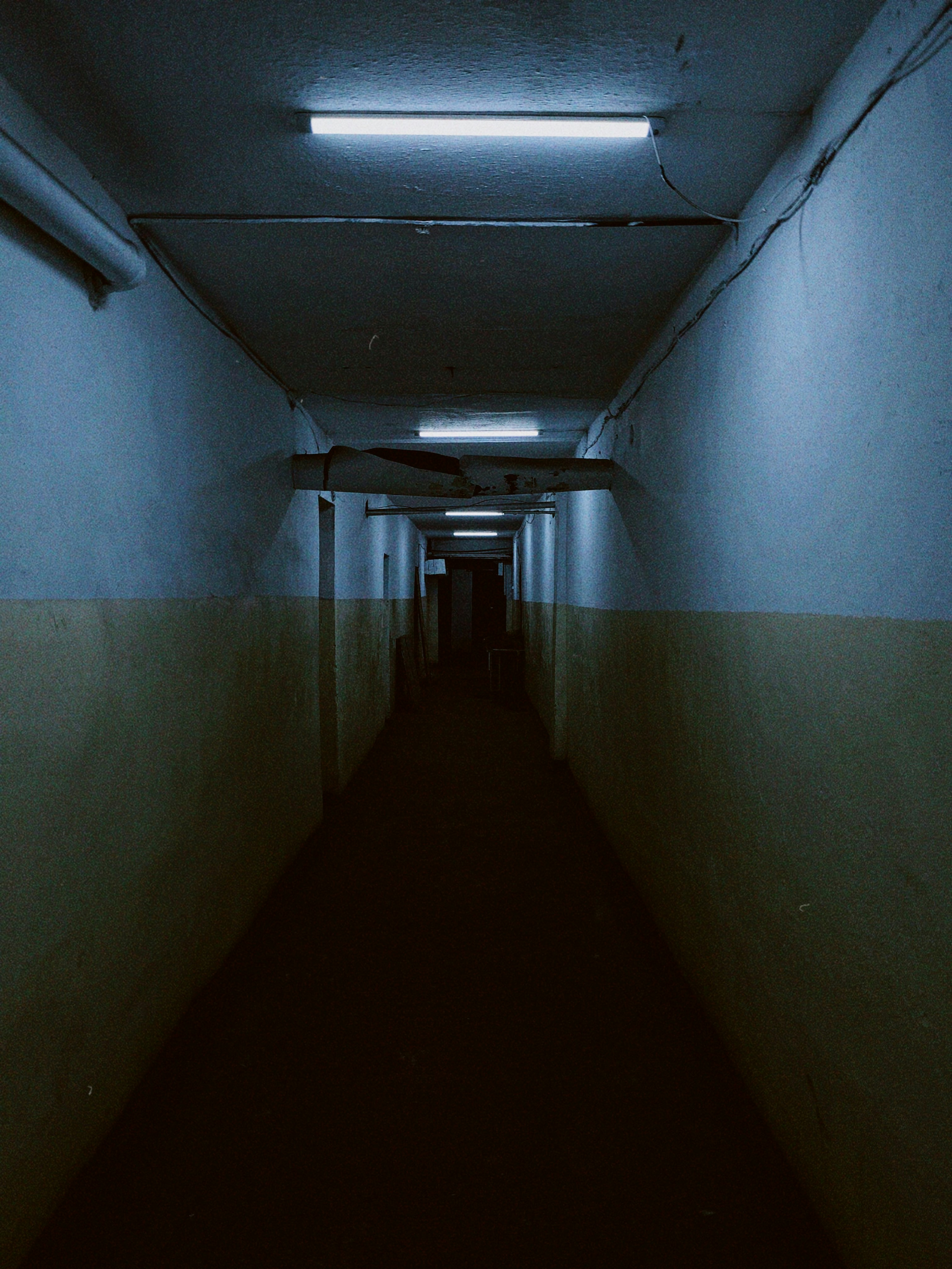 a long dark hallway with a light at the end