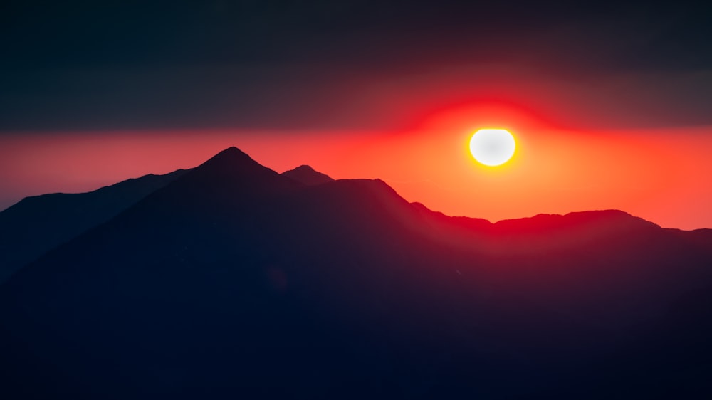 the sun is setting over a mountain range