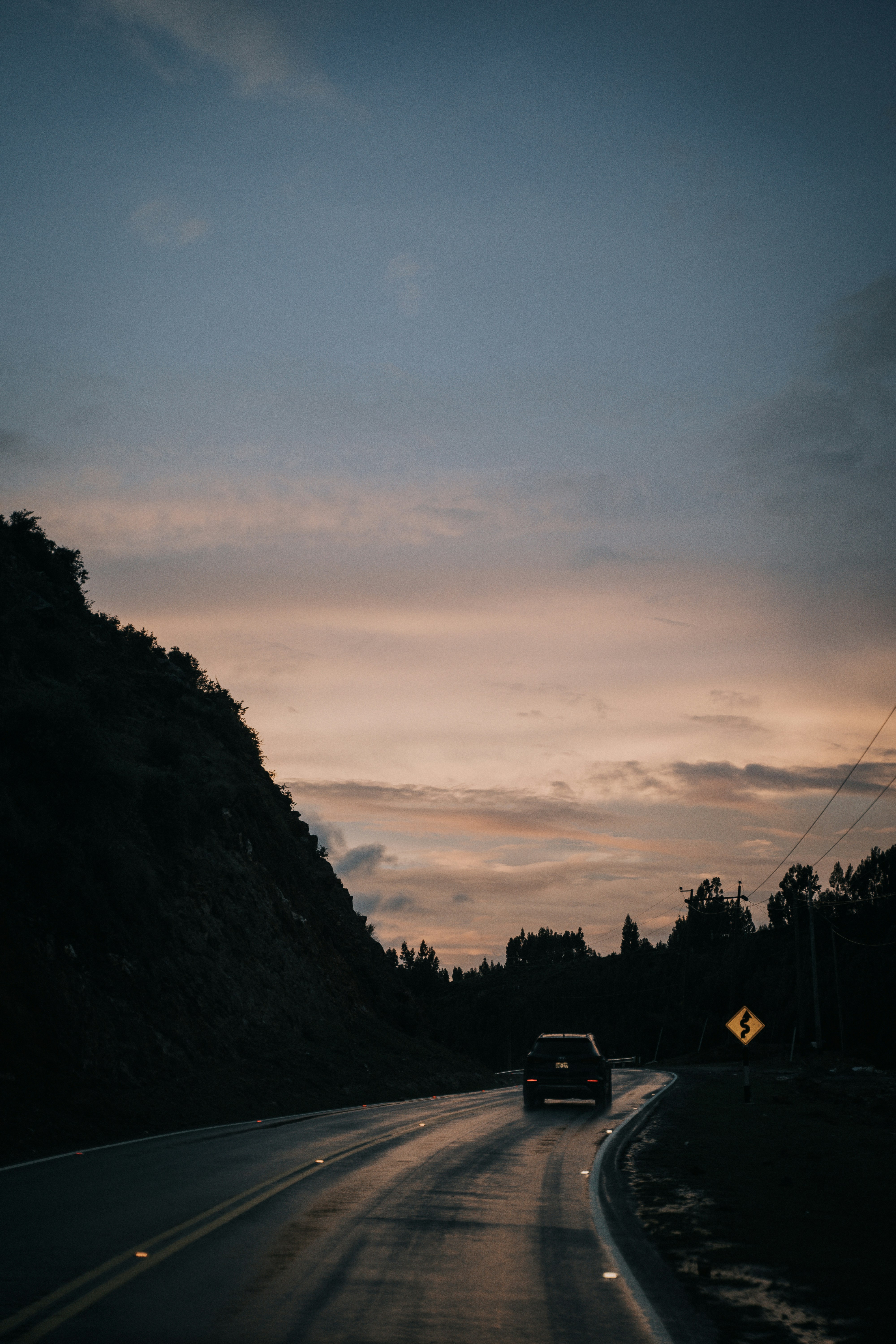 a car driving down a road with a mountain in the background