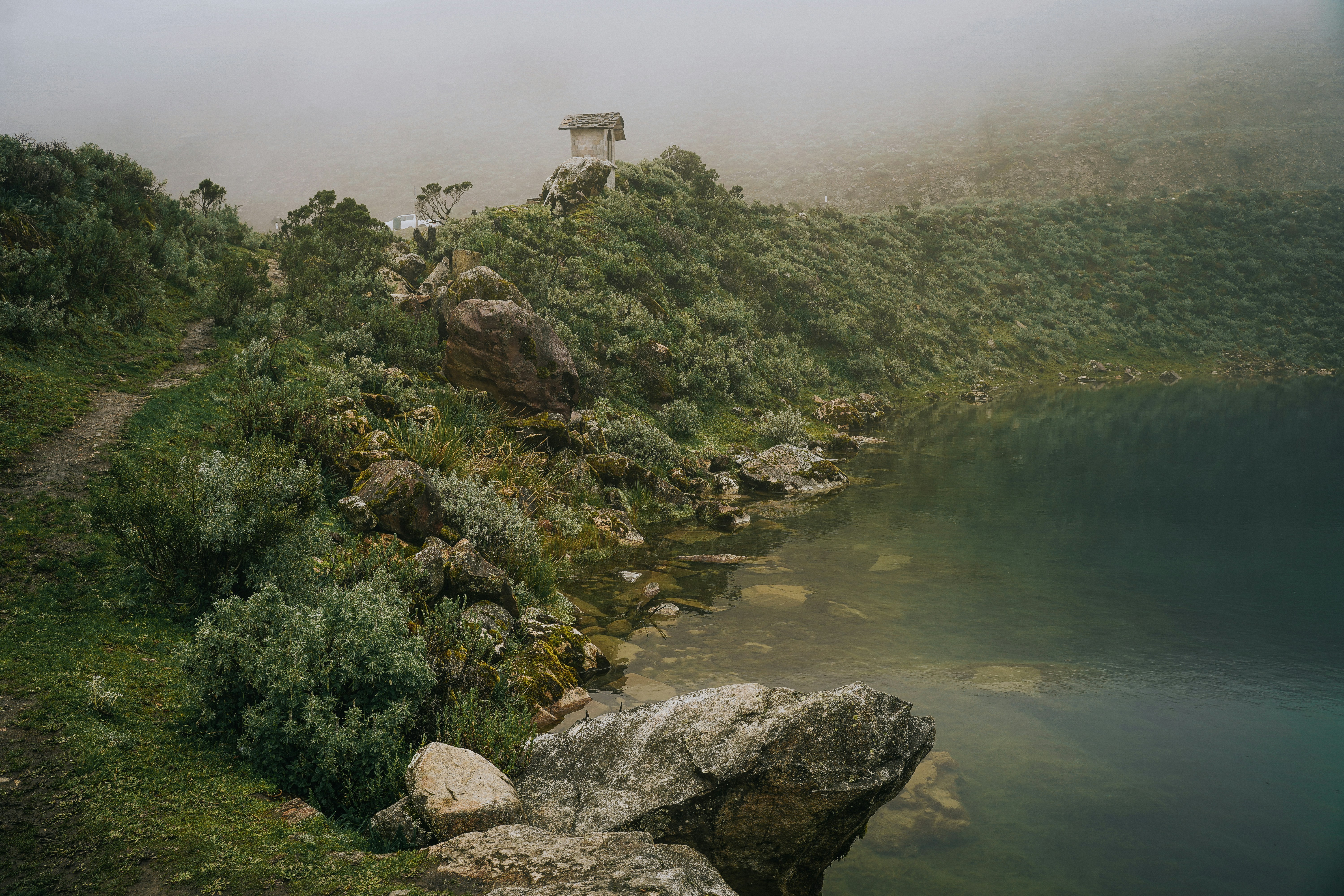 a mountain with a lake and a house on top of it
