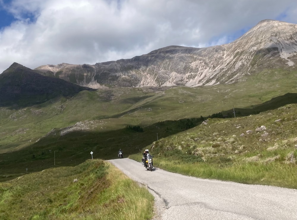 a couple of people riding motorcycles down a road