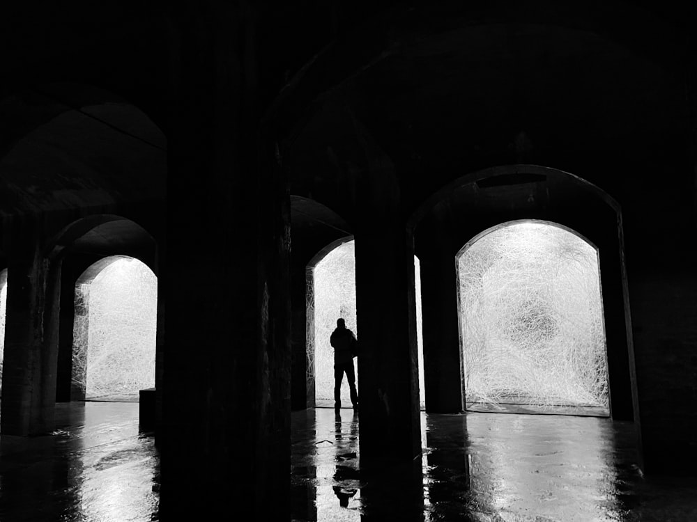 a black and white photo of a person standing in a dark room