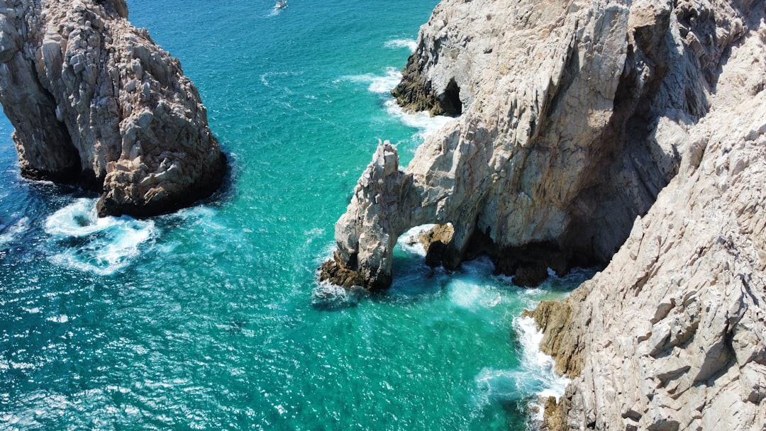 an aerial view of a body of water next to some rocks, Cabo Mexico