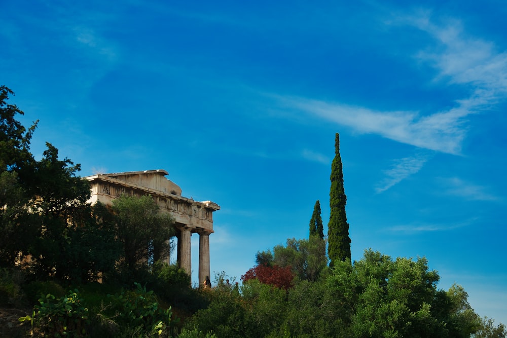 a building with columns and trees in front of a blue sky