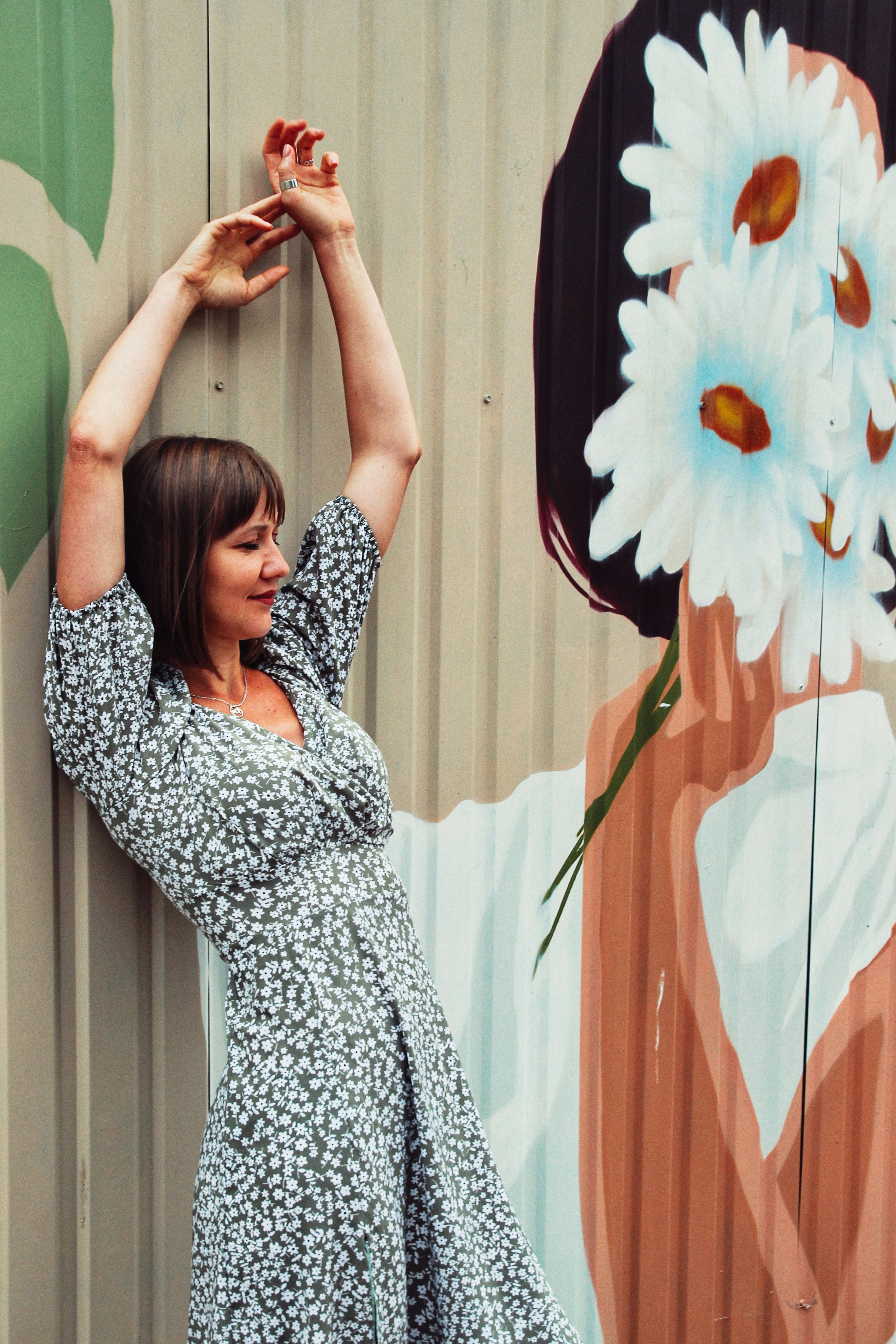 A woman standing in front of a wall with a flower on it photo – Free ...