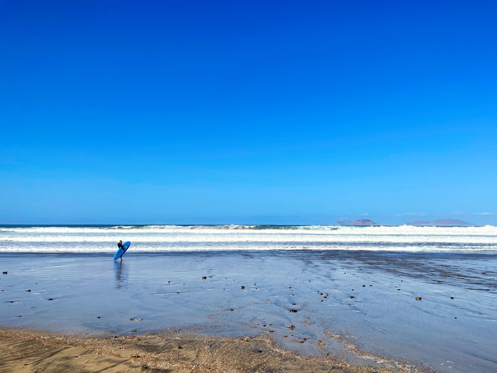 a person standing on a beach holding a surfboard