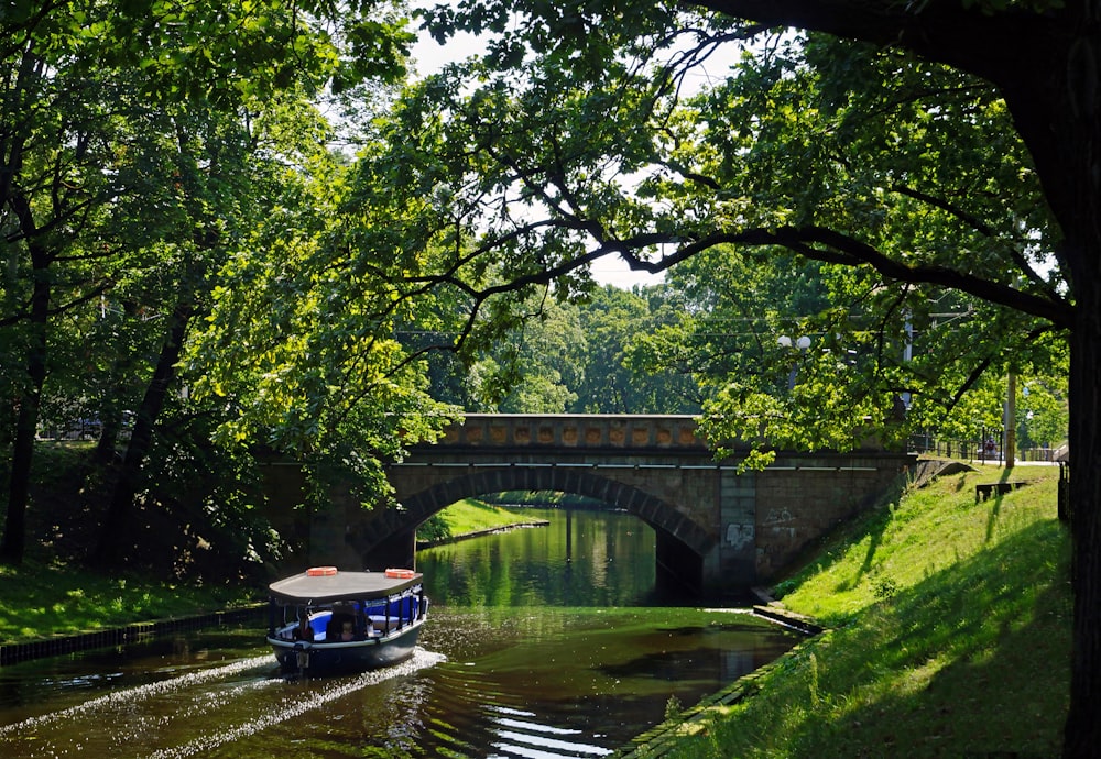 a boat traveling down a river under a bridge