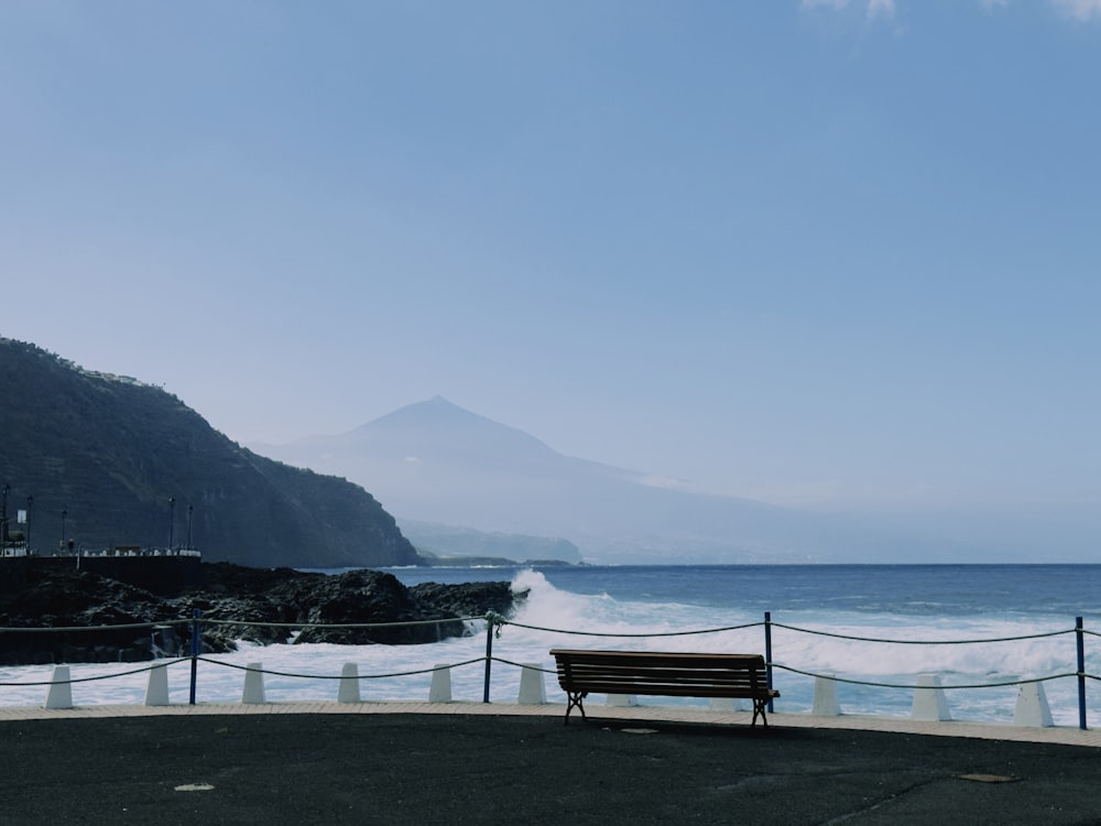 a bench sitting on the side of a road next to the ocean