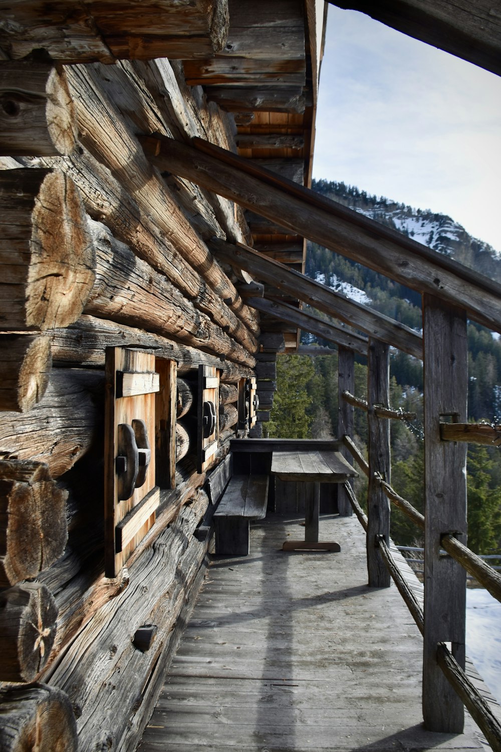 a wooden porch with a bench and a wooden fence