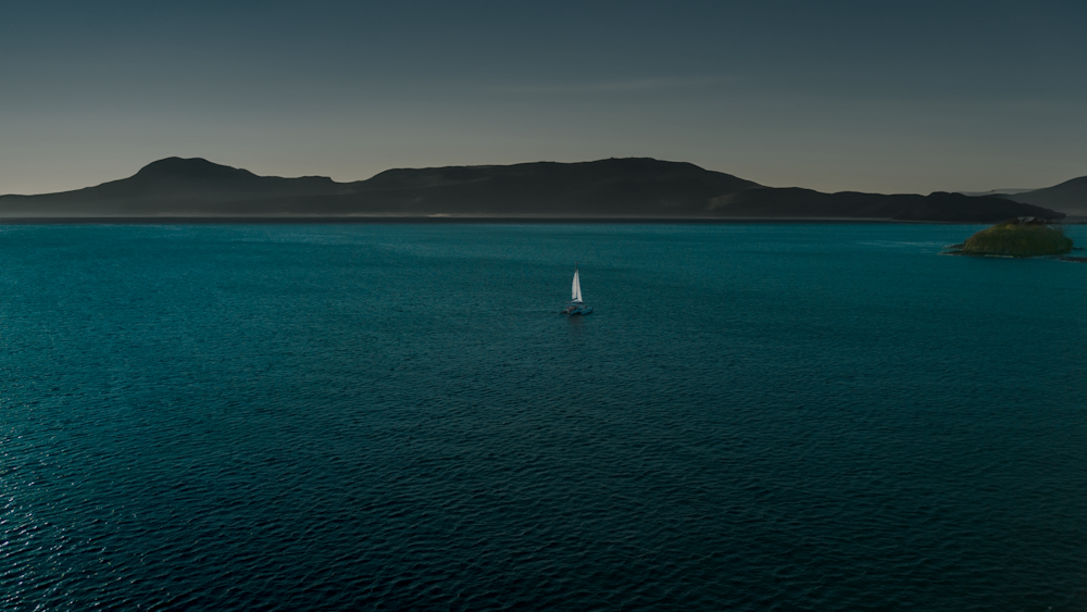 a lone sailboat in the middle of a large body of water