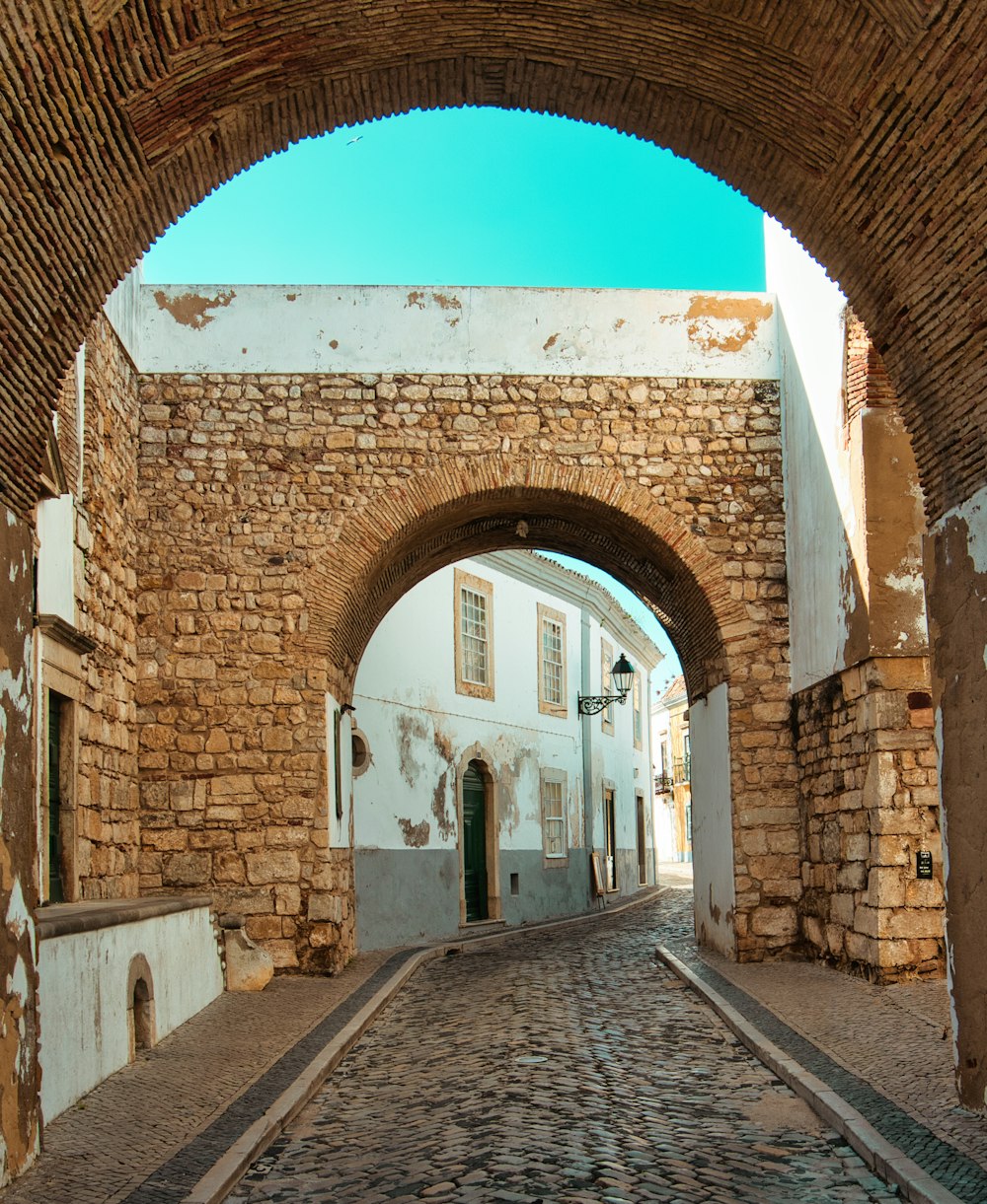 a cobblestone street with an arch in the middle