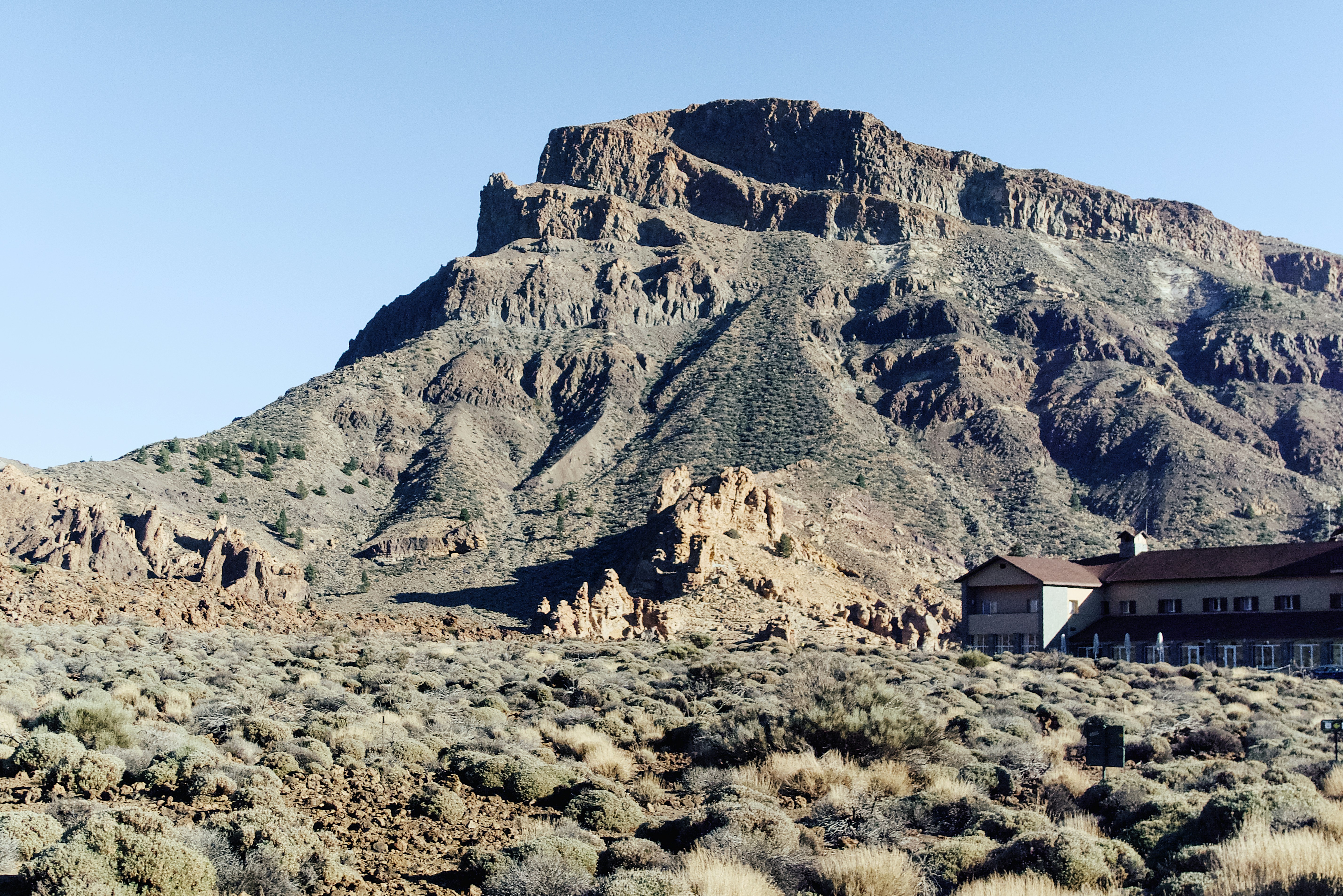 a house in the middle of a desert with a mountain in the background