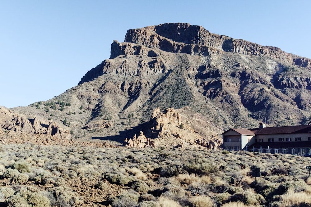 a house in the middle of a desert with a mountain in the background