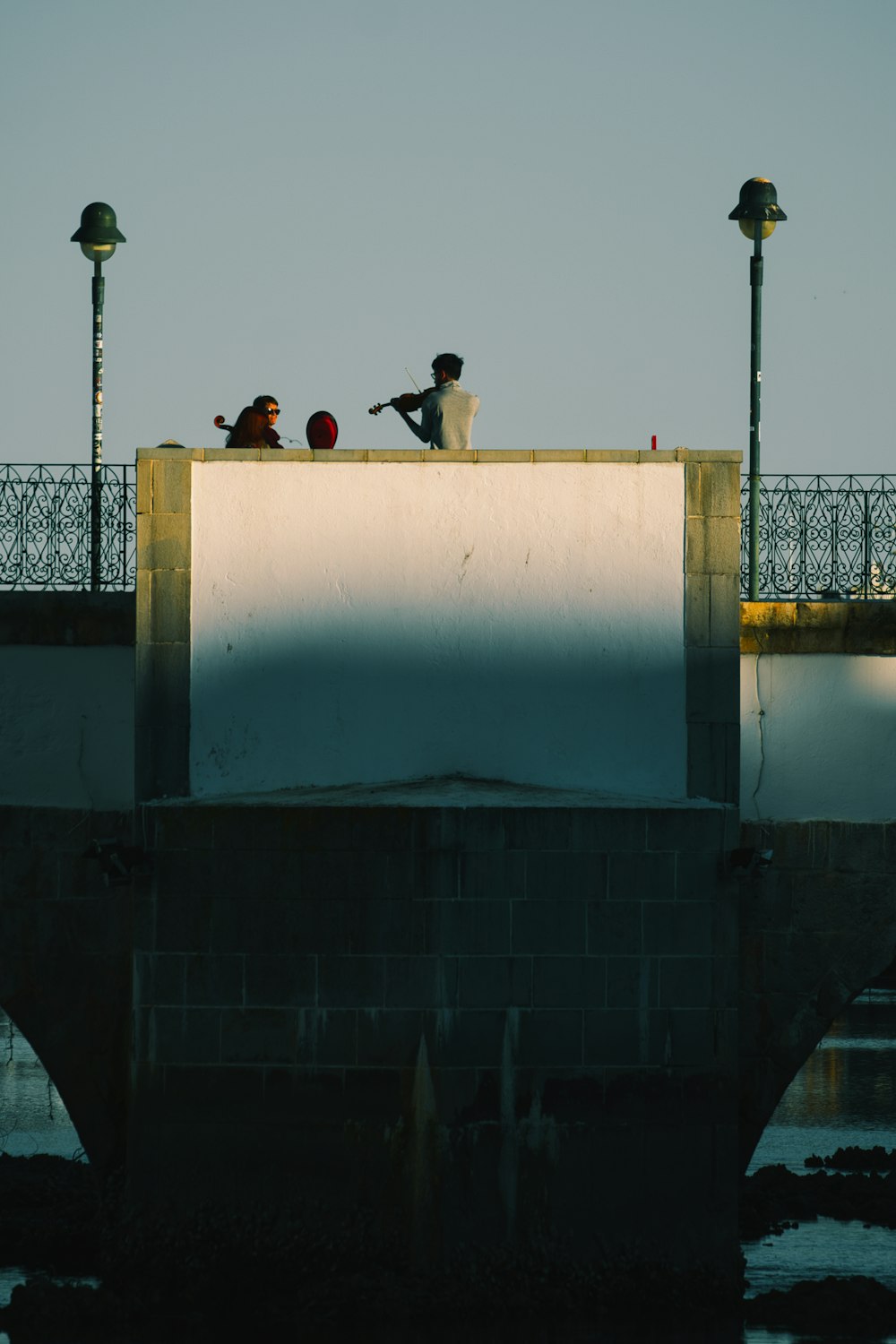 three people sitting on top of a bridge
