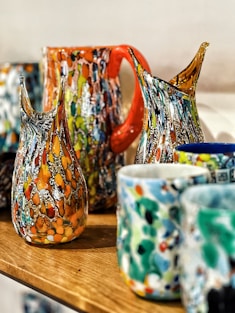 a wooden table topped with lots of colorful vases