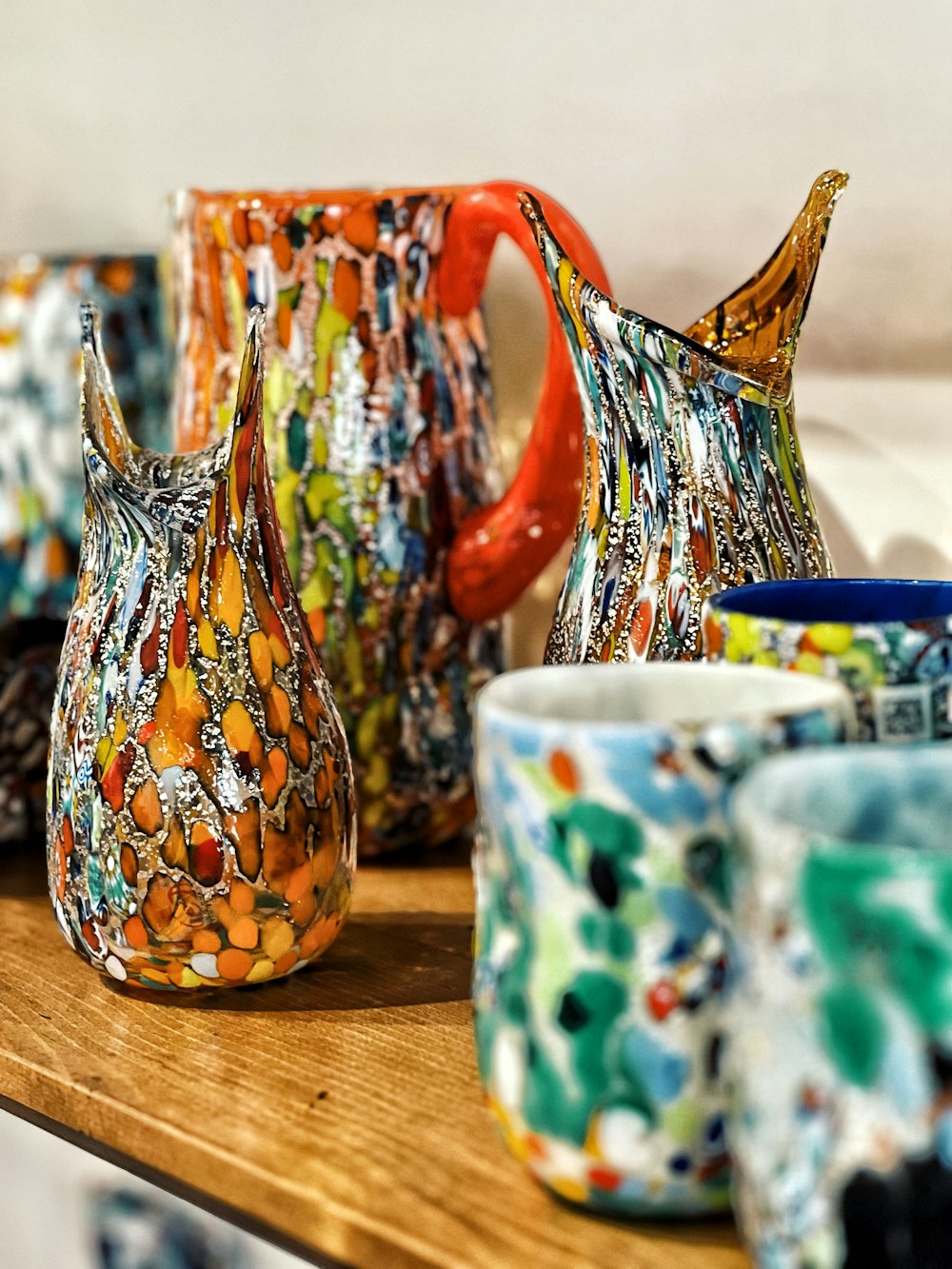 a wooden table topped with lots of colorful vases